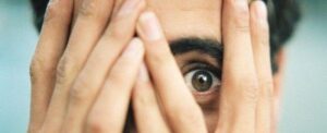 Un uomo si copre il viso con le mani e sbircia tra le dita.