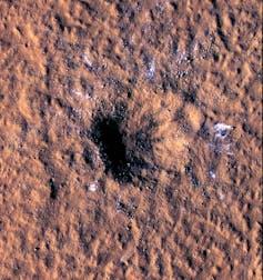 Una foto satellitare di un cratere su terreno rosso.