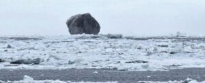 Un iceberg nero tra piccoli pezzi di ghiaccio in mare
