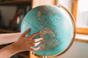 un bambino punta la mano verso il Sud America su un globo