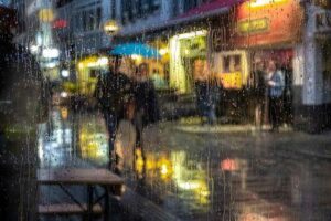 Una coppia passeggia per la città sotto la pioggia, con gocce d'acqua sull'acqua.