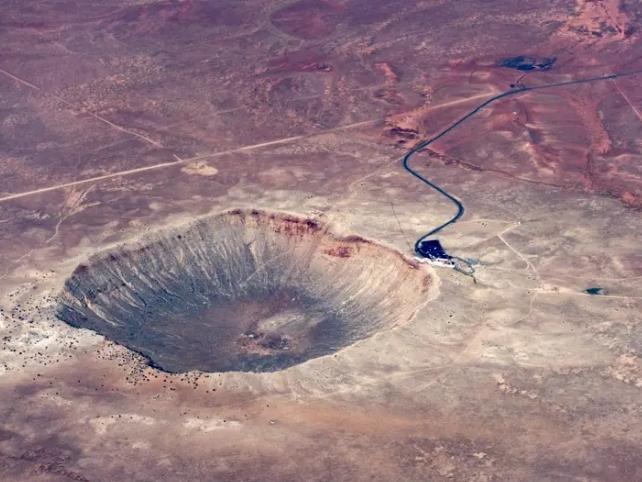 Grande cratere di meteorite in terreno rosso desolato