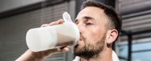 Uomo muscoloso che beve un frullato proteico