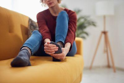 Una donna seduta su un divano che si strofina il piede