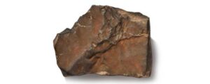 una roccia rosso-brunastra su uno sfondo bianco.