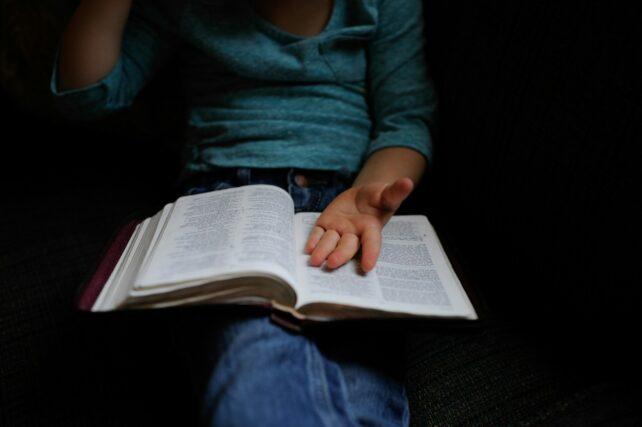 bambino che tiene un libro aperto