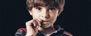 ragazzo che si morde le unghie in un ritratto in studio che guarda la fotocamera
