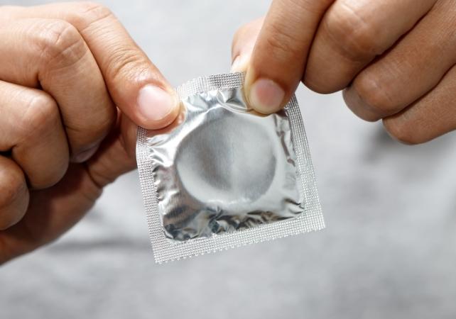 uomo che apre un preservativo