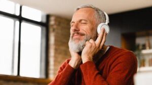 un uomo di mezza età indossa delle cuffie e ascolta musica con un'espressione soddisfatta sul volto
