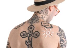uomo con tatuaggi e crema solare
