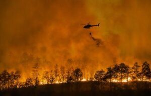 L'elicottero antincendio trasporta un secchio d'acqua per estinguere l'incendio forestale.
