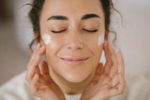 Donna che applica crema per la cura della pelle sulle guance