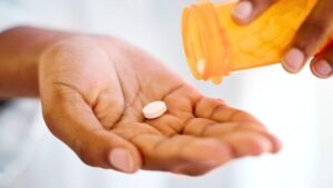 Compresse bianche generiche versate in una mano da una bottiglia di prescrizione