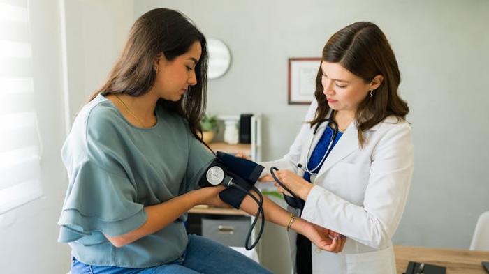 Una giovane donna ha la pressione sanguigna controllata da una dottoressa.