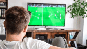 uomo seduto sul divano a guardare il calcio in tv
