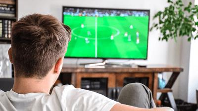 uomo seduto sul divano a guardare il calcio in tv
