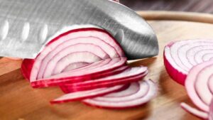 Coltello che taglia cipolle rosse da vicino