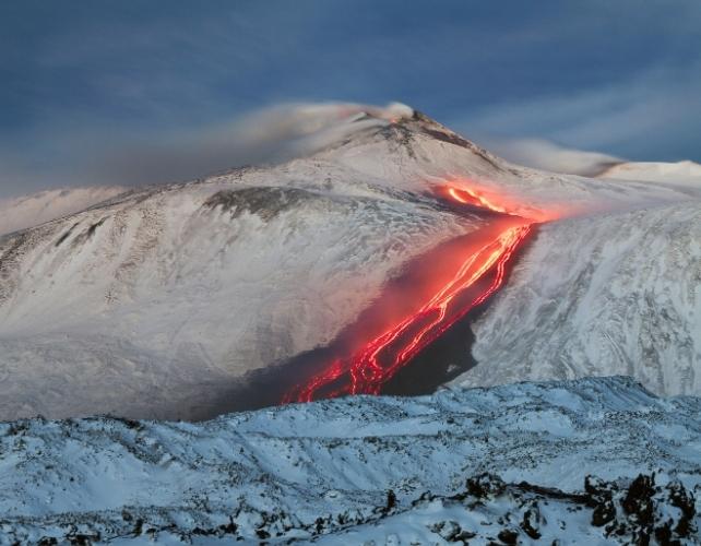 Lava che scorre lungo il lato di un vulcano coperto di neve