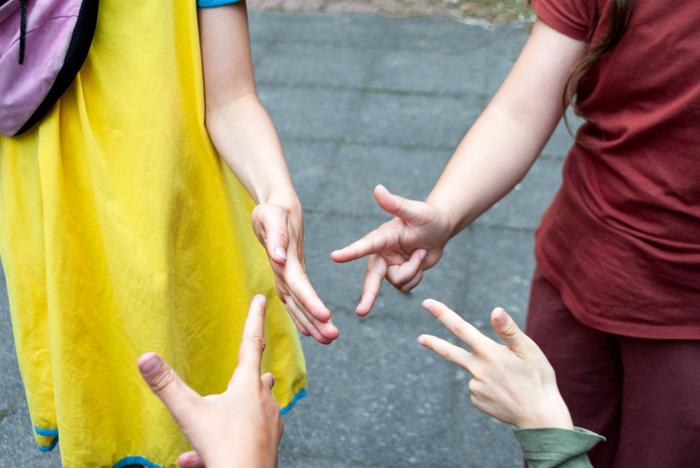 Mani di quattro bambini che giocano a carta, forbice, pietra