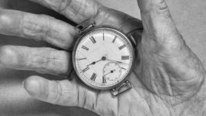 Un quadrante di orologio da polso antico incrinato nella mano di una donna anziana