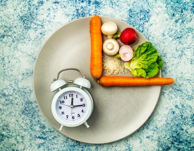 Verdure su un quarto di piatto, con un orologio sull'altro quarto