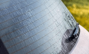 Finestrino posteriore dell'auto coperto di gocce di pioggia e acqua