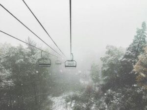 Una scena invernale da una seggiovia circondata da neve che cade e alberi alpini