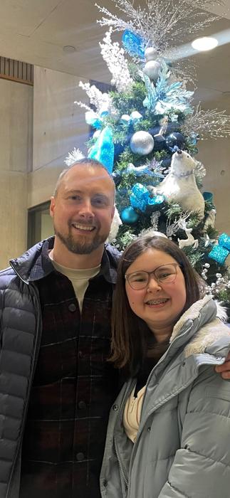 ragazza giovane e suo padre in piedi davanti a un albero di Natale decorato con ornamenti blu e argento