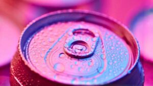 Immagine ad alto contrasto di una lattina di soda blu e rosa o di un'altra bevanda, coperta di gocce d'acqua