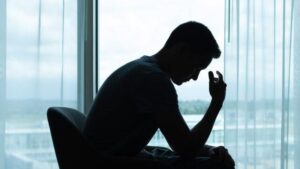 Uomo pensieroso in una stanza buia con la testa china