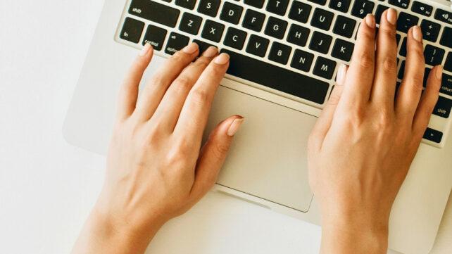 Immagine ravvicinata di mani che digitano su una tastiera di laptop
