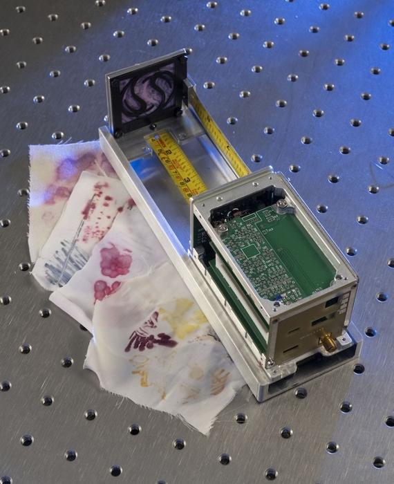 Esempi del tessuto dipinto con coloranti batterici si trovano accanto al satellite Spinning Around SpinnyONE che lo porterà nello spazio il prossimo anno