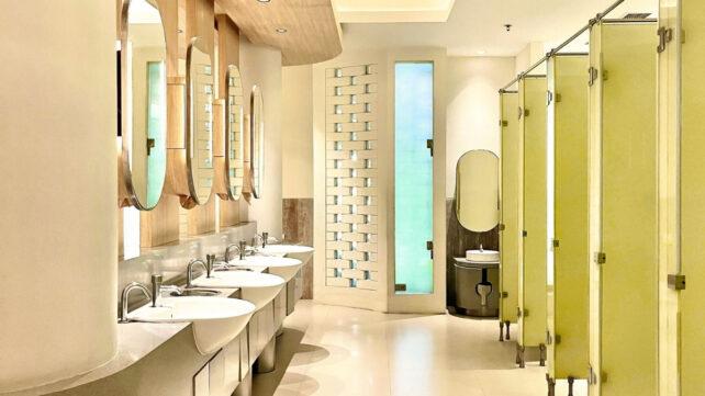 Una fila di cabine di bagno pubbliche con specchi e lavandini di fronte