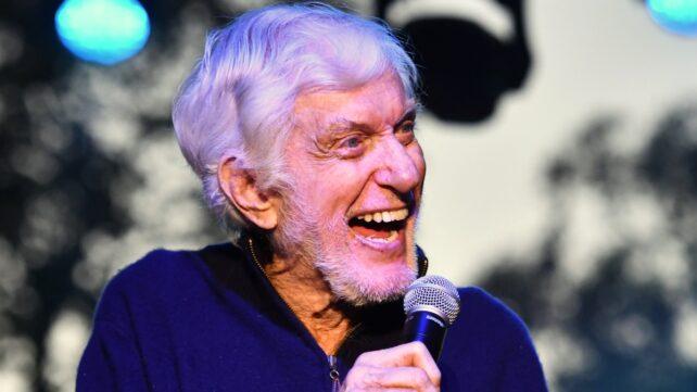 Un Dick Van Dyke sorridente che parla in un microfono sul palco