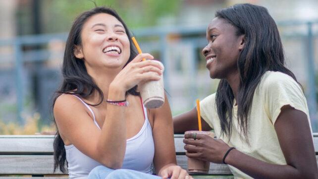 Due giovani adulti che gustano bevande da asporto su una panchina all'aperto