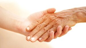 Una mano dall'aspetto giovane che tiene la mano di una persona anziana
