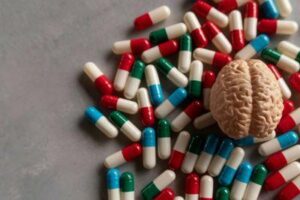 modello 3D piccolo di un cervello su un mucchio di capsule di pillole di diversi colori, su un tavolo
