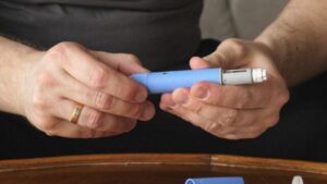 primo piano di una penna per iniezione di semaglutide nelle mani di un uomo