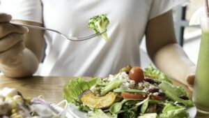 Messa a fuoco selettiva di una donna con broccoli e insalata