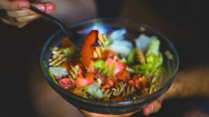 Mano che tiene una forchetta con una ciotola di insalata