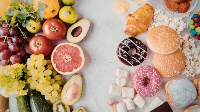Immagine di uno spazio bianco con frutta fresca e sana a sinistra e cibi lavorati a destra