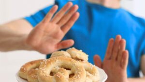 Le mani di una persona sollevate davanti a un piatto di pretzel, come per rifiutare l'offerta
