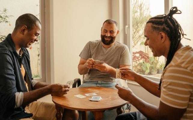 tre uomini a un tavolo che giocano a un gioco di carte