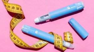 penna di semaglutide e nastro di misurazione su uno sfondo rosa