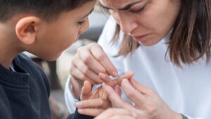 madre che rimuove una scheggia dal dito di suo figlio