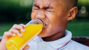 ragazzo che fa una smorfia mentre beve succo d'arancia