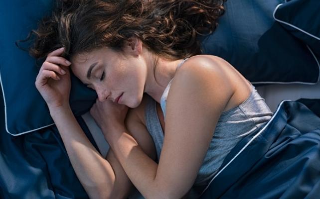 donna che dorme su lenzuola blu