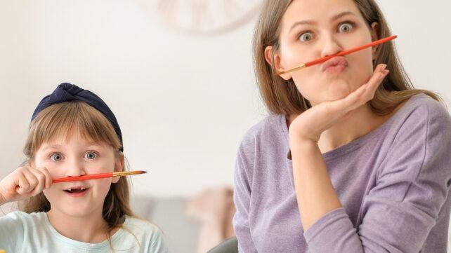 Una madre e un bambino che si divertono con le penne bilanciate sulle labbra