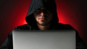Hacker che usa un laptop alla luce rossa su sfondo scuro