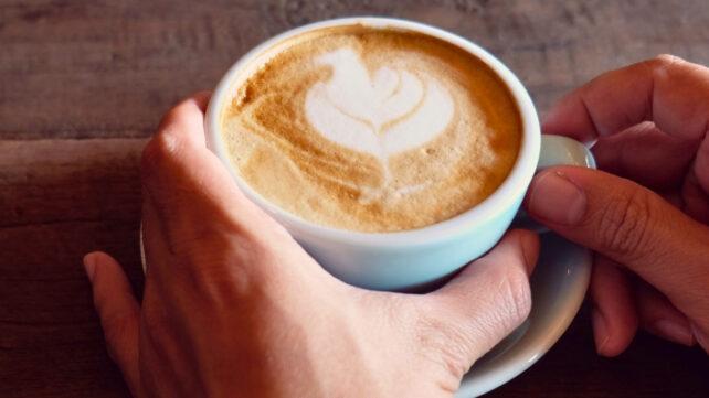 Mani che tengono una tazza di caffè dal look rustico